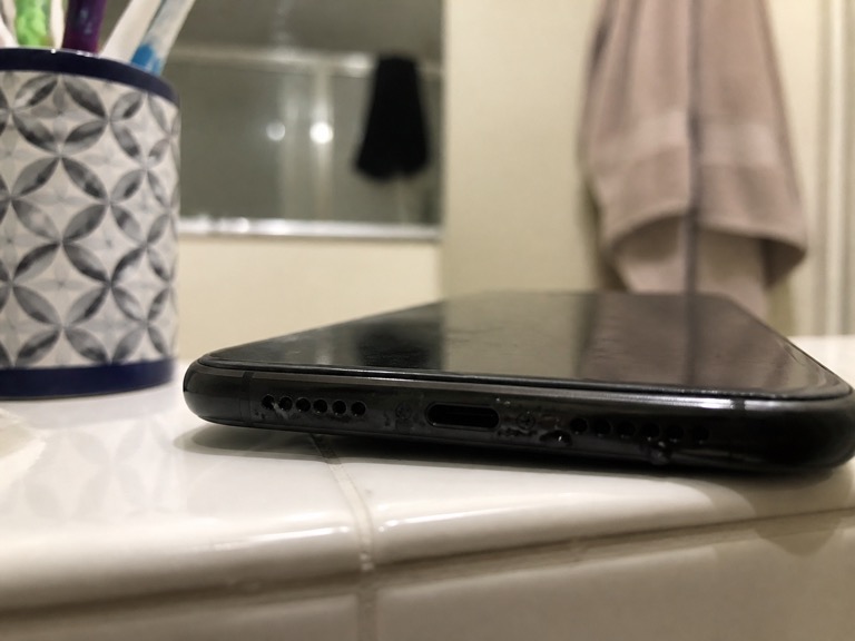 Speaker opening at the bottom edge of a phone with water droplets
